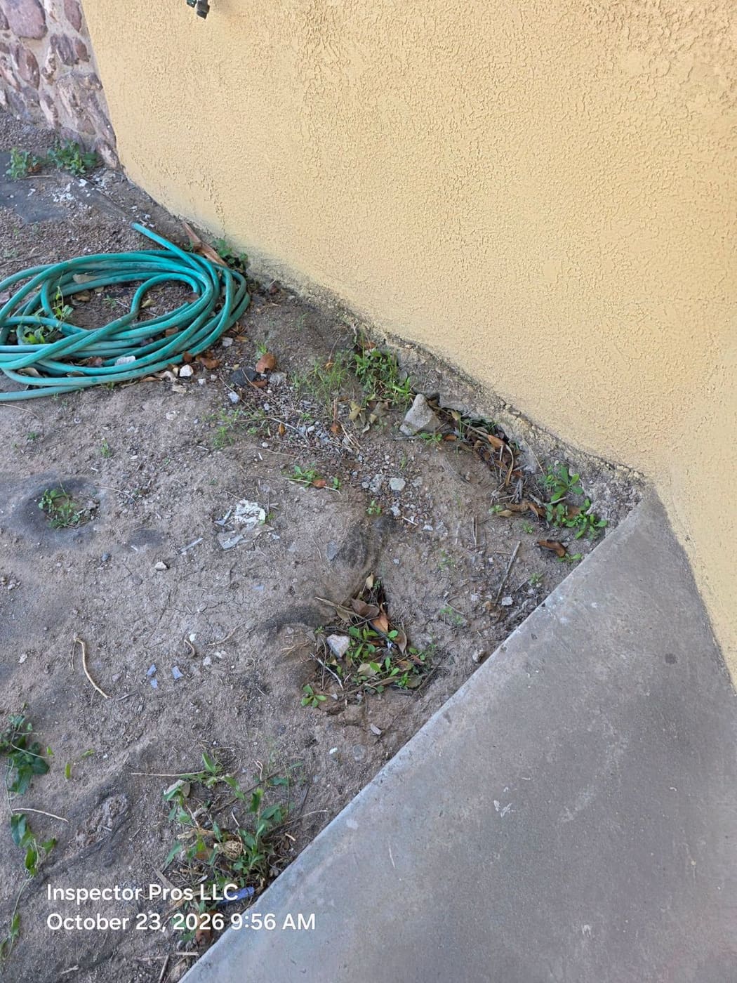 Eroded soil along the slab edge beside a concrete patio