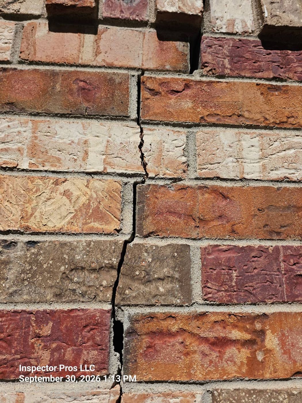 Close-up of a crack running straight through brick rather than the mortar joints