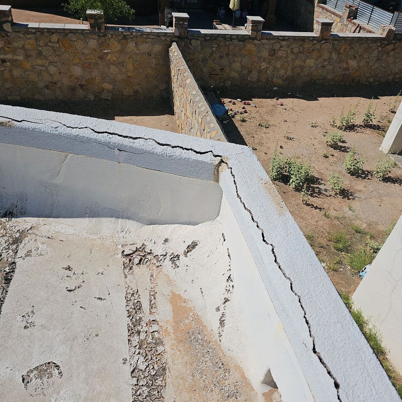 Dirt staining in a low corner of a flat roof next to a cracked parapet