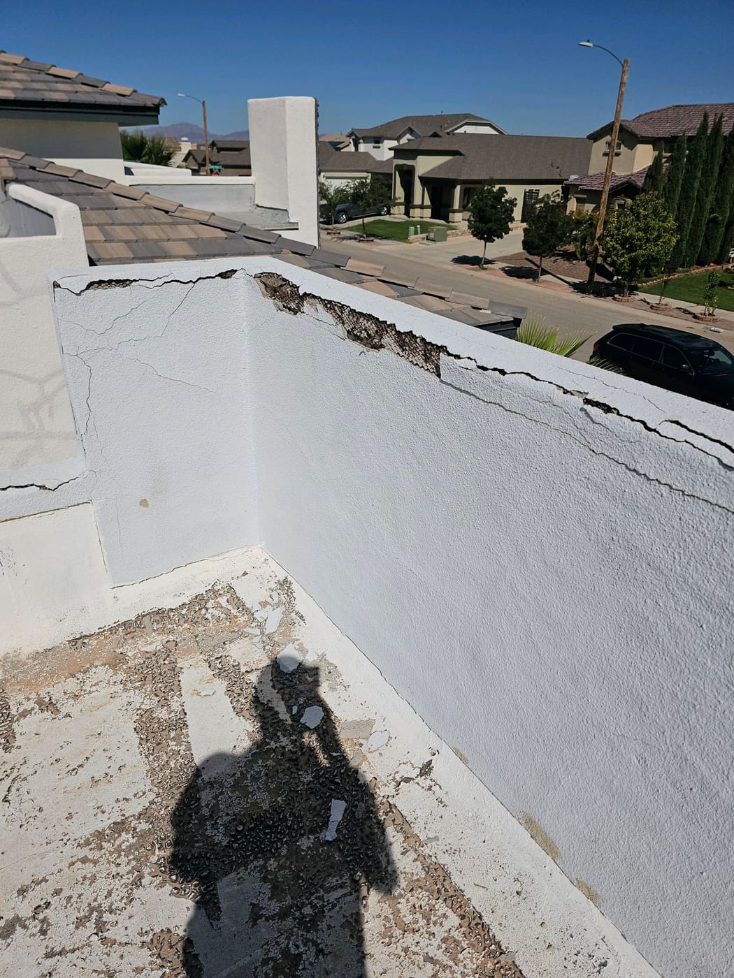 Cracked stucco on top of a parapet wall with metal lath exposed