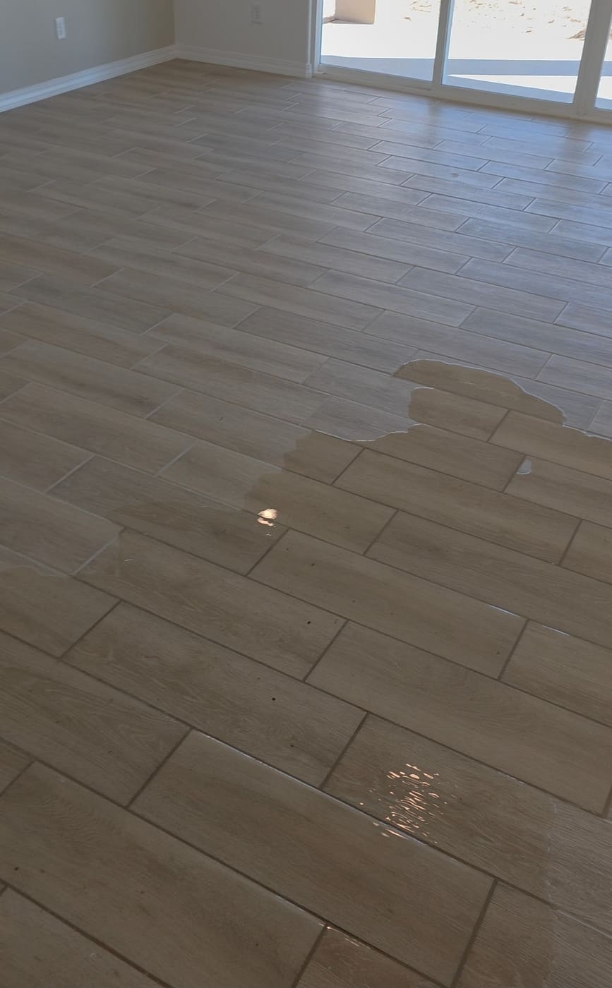 Water spread across the tile floor of an empty new construction home after a sewer backup