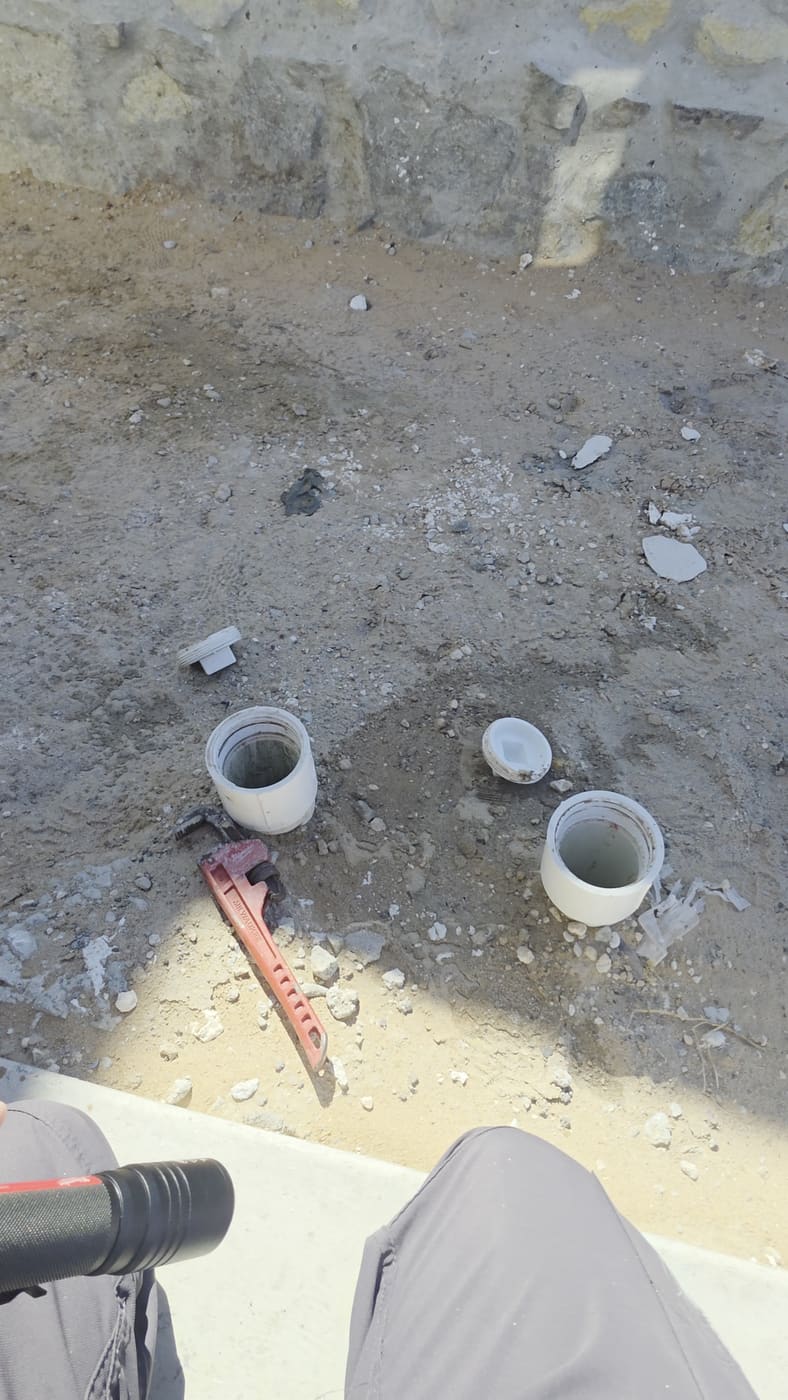 Two sewer cleanouts in the dirt at the front of a newly built home