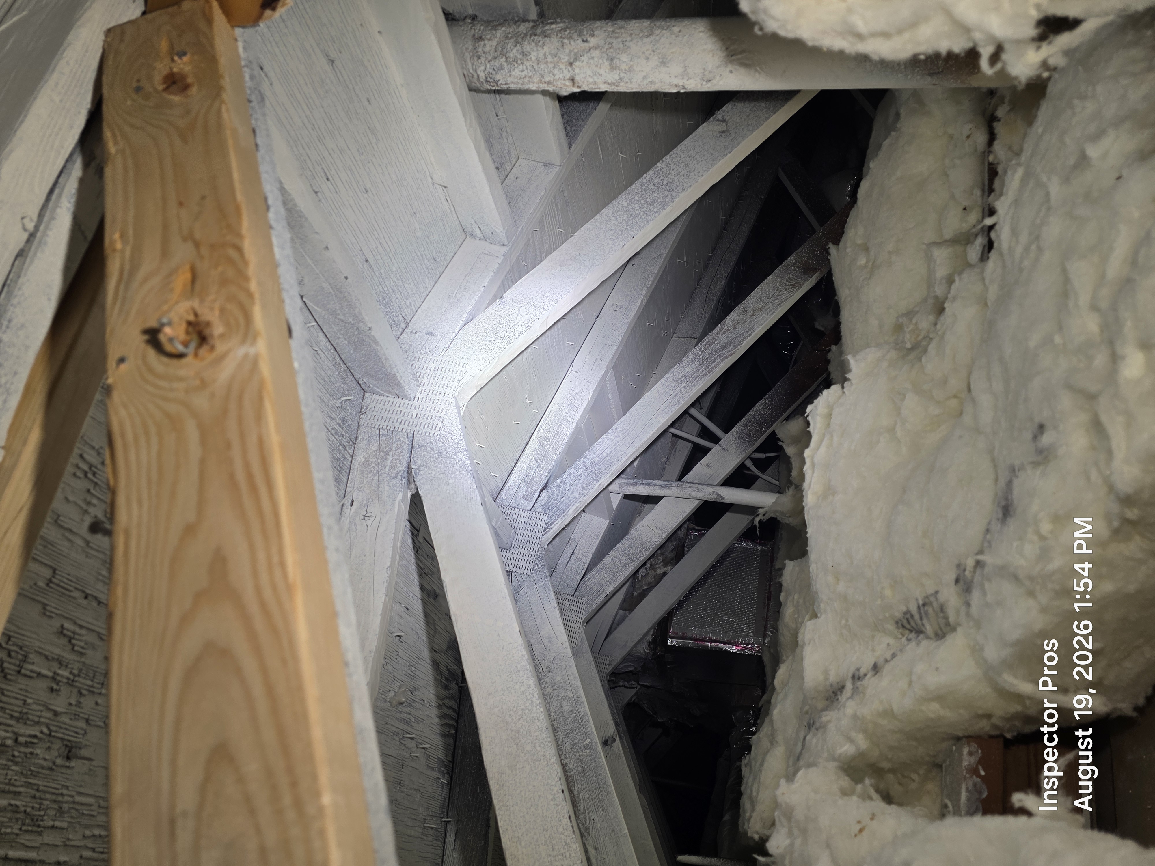 Fresh sistered lumber next to fire-damaged painted attic structure